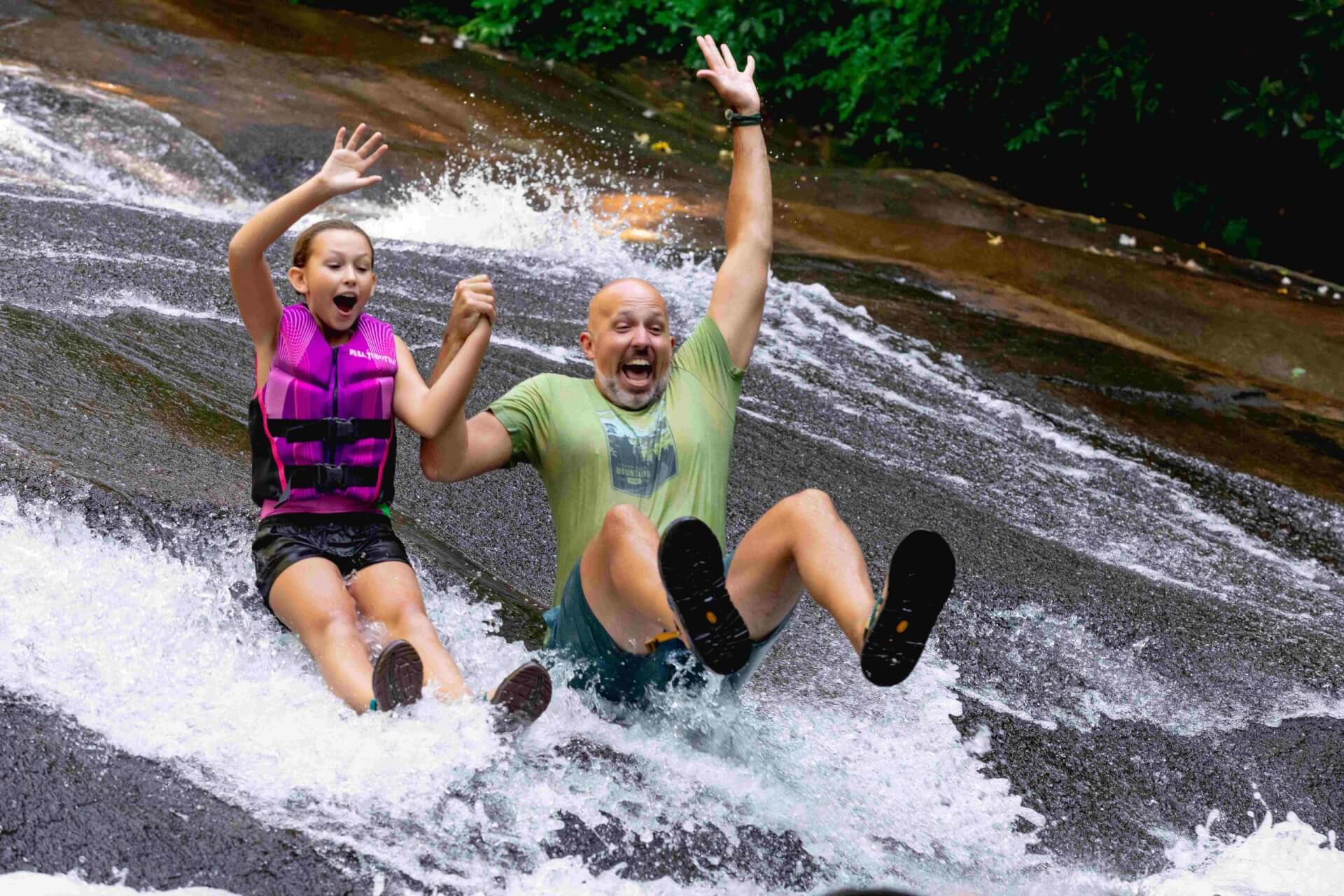 A dad and daughter going down Sliding Rock in Western North Carolina's Pisgah National Forest, just outside of Brevard